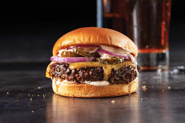 ادویه های مناسب برگر کدامند؟ یک همبرگر که با مواد مختلف مثل پیاز پنیر چدار روی میز رستوران قرار گرفته اند